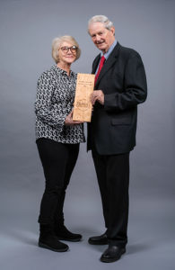 Jim Gaines holding award with his wife