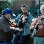 Three men playing Appalachian string instruments outdoors