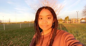 Picture of Alise with an orange sweater in a field