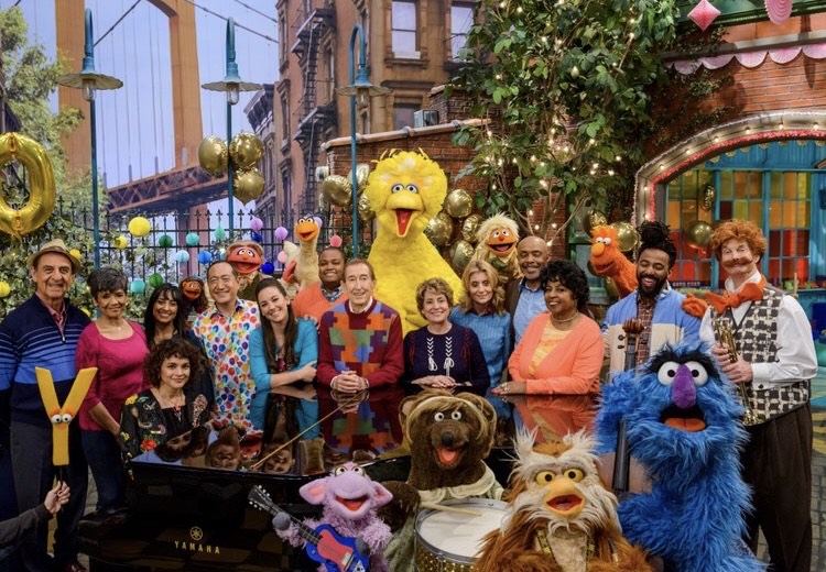 Hayes stands with full Sesame Street cast and characters