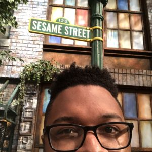Hayes takes a photo of himself in front of the beloved Sesame Street sign
