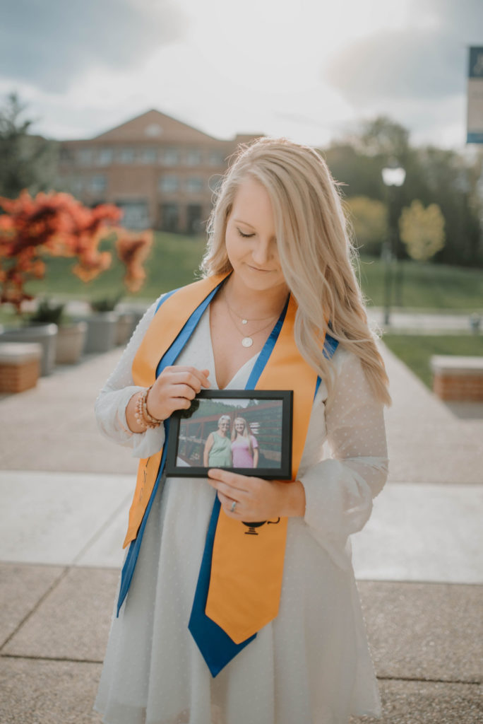 Wearing graduation sashes, Elizabeth holds her favorite photo with her late grandmother. Photographer: Andreea Teban