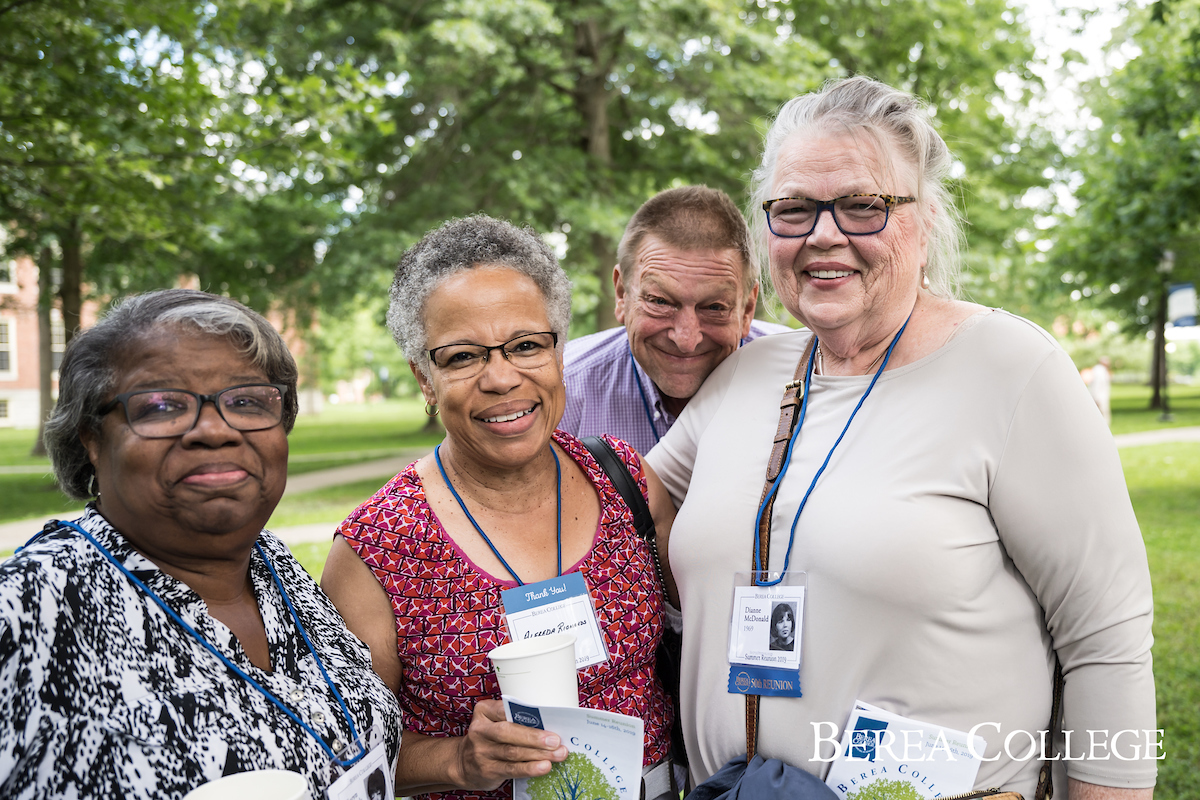 Four alumni smiling for a photo