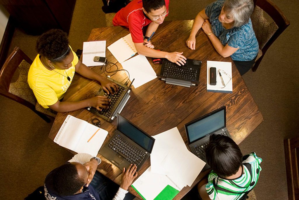 Group of students at a table with laptops