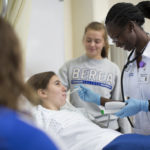 A nursing student measuring temperature of a patient