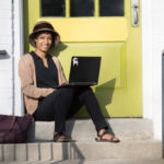 Jasmine Towne, Student Stories Associate, sits outside with laptop