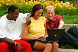 Students outside gathered around a laptop